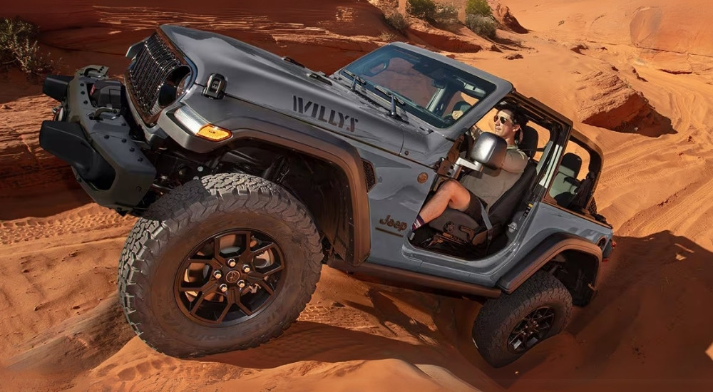 A grey 2025 Jeep Wrangler Willy's is shown off-roading.