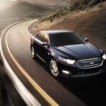 A black 2014 Ford Taurus Limited is shown driving after viewing a used Ford for sale.