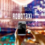 A person is shown holding a cellphone with "Robotaxi" written above.