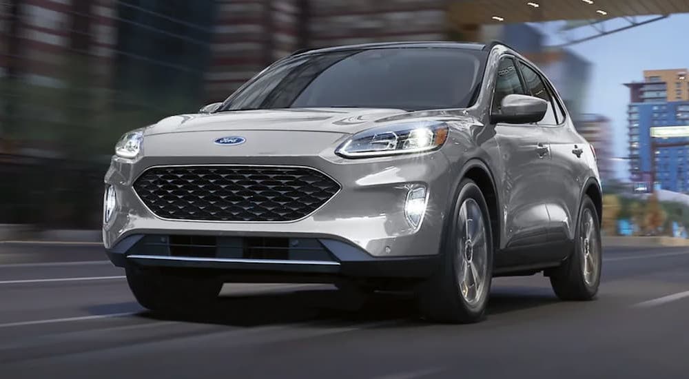 A silver 2021 Ford Escape driving through a city from a used car dealer.