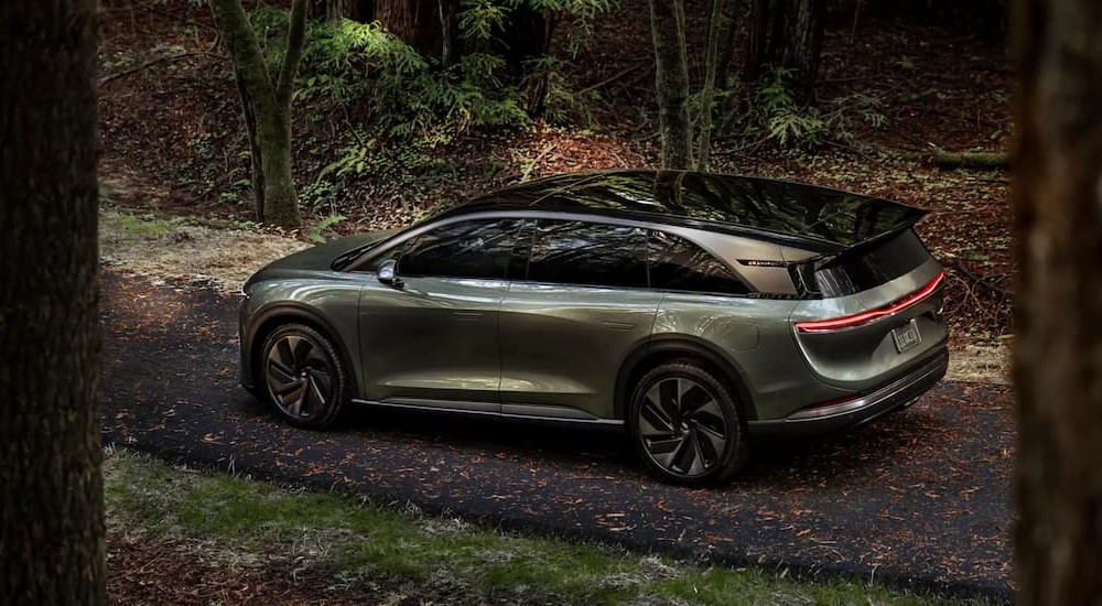 A green 2025 Lucid Gravity is shown parked near a forest.