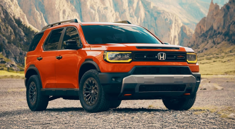An orange 2026 Honda Passport parked off-road.