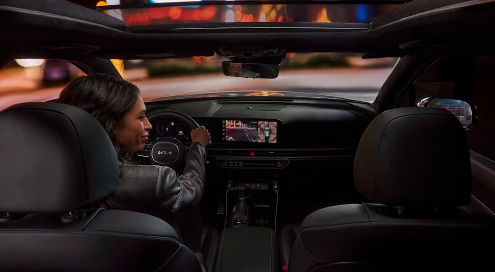 Woman test driving a 2025 Kia Sorento for sale in a city.
