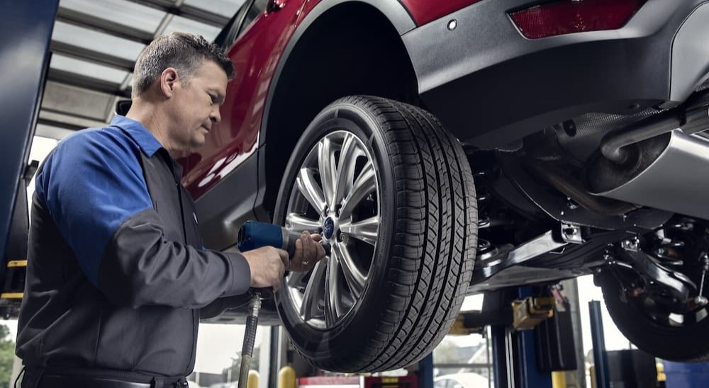 A technician is shown working on a red vehicle.