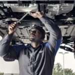 A mechanic is shown working on a Used Ford for sale near Cohoes.