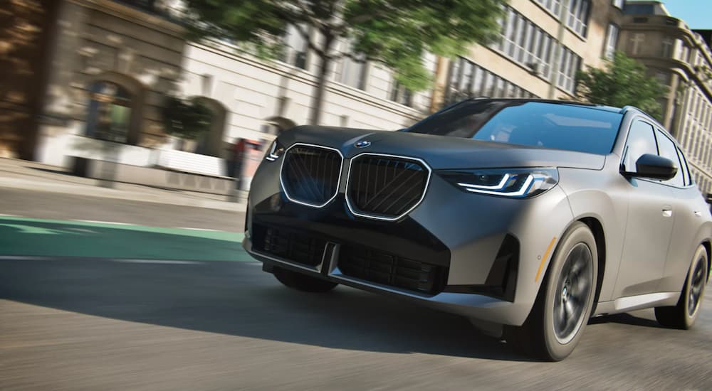 Gray 2025 BMW X3 for sale driving down a city street