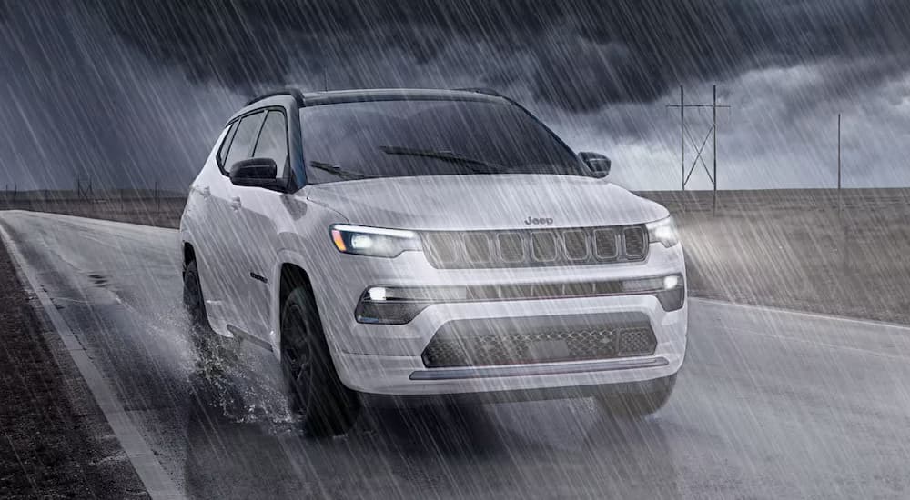 White 2025 Jeep Compass driving in the rain