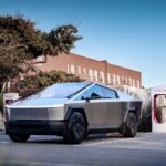 A 2025 Tesla Cybertruck is shown charging at a NACS charge station.
