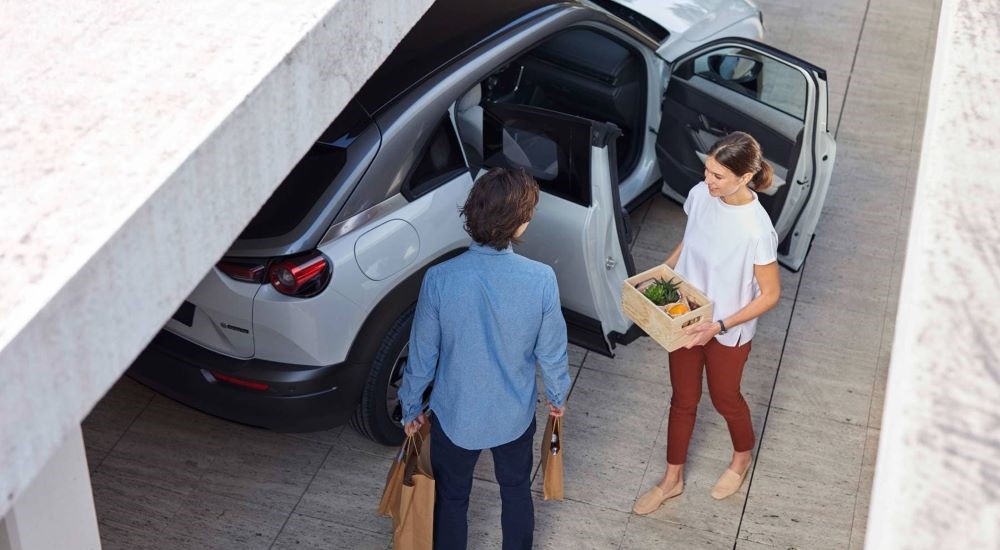 Two people unloading groceries from a 2023 Mazda MX-30