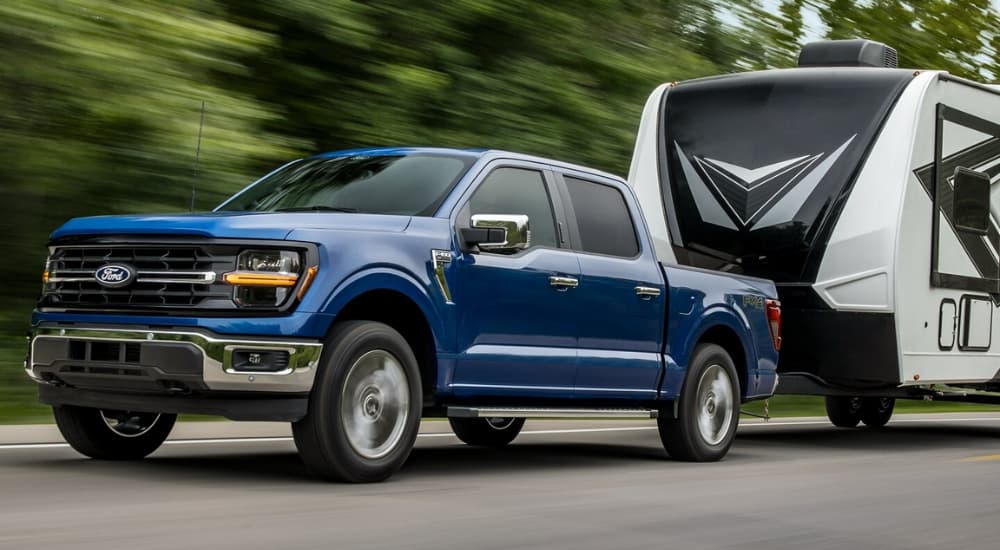 A blue 2025 Ford F-150 towing a camper