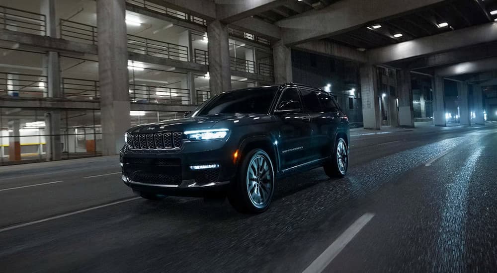 A black 2025 Jeep Grand Cherokee driving down a city street