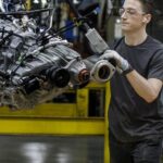 A man in a Ford plant putting a vehicle together