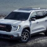 A white 2025 GMC Acadia AT4 parked near water.