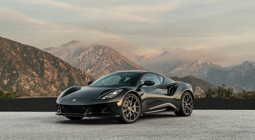 A black Lotus Emira parked near a mountain range.