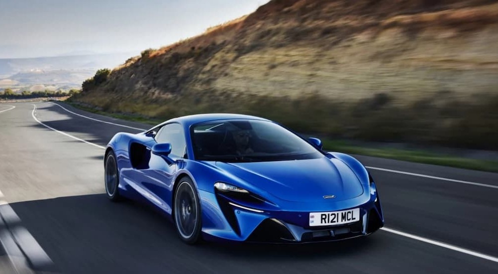 A blue McLaren Artura Hybrid driving on a highway.