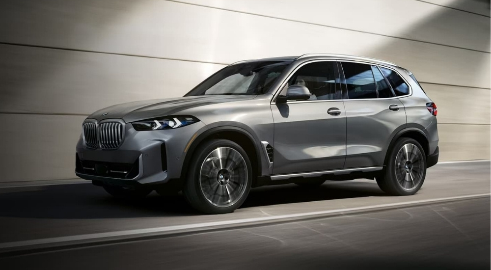 A silver used 2024 BMW X5 driving down a road