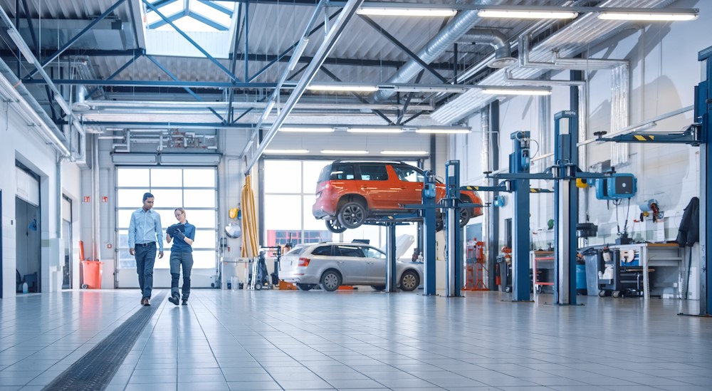 Two people walking in an automotive garage.