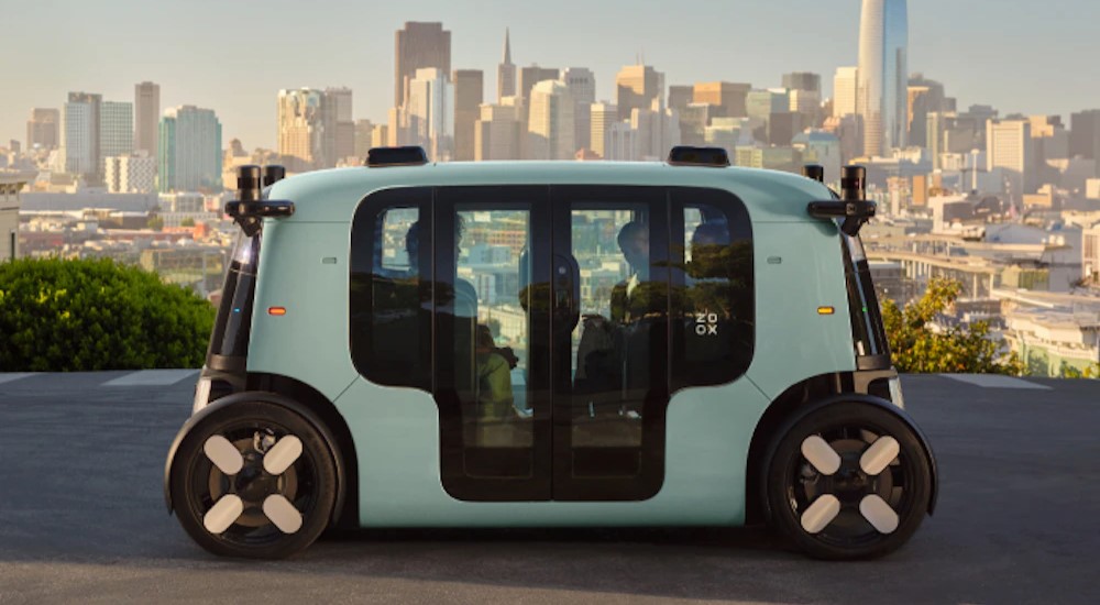 An aqua Zoox robotaxi parked near a city.