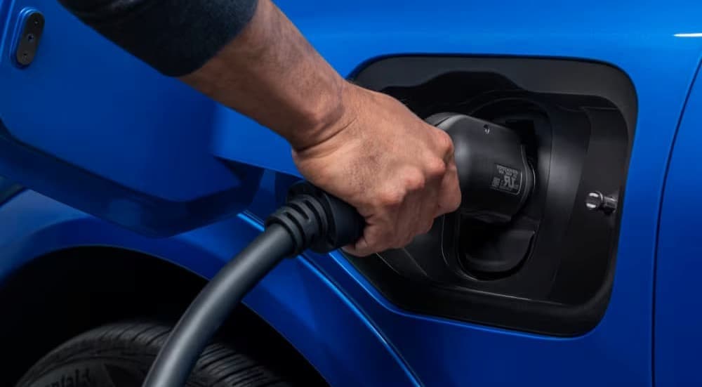 A person charging a blue 2025 Chevy Equinox EV.