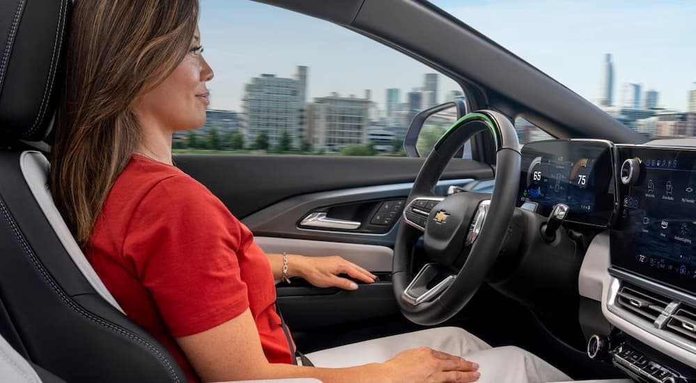 A person driving in a 2025 Chevy Equinox EV for sale.