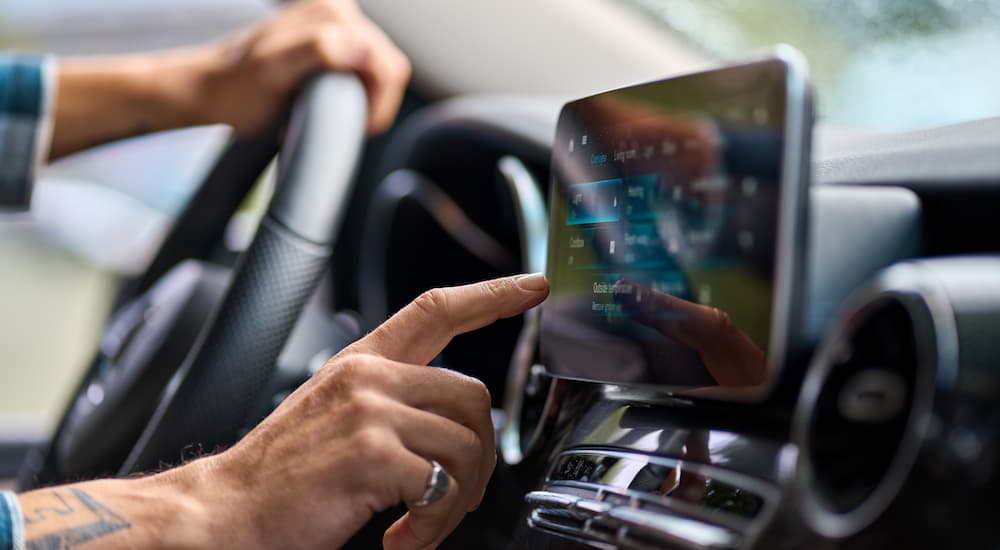 A man using the infotainment display in his EV to find a charging station