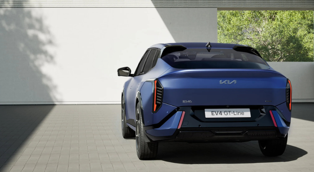 Blue 2026 Kia EV4 Fastback GT from the rear pared in front of a Kia Dealer.