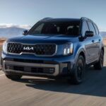 Black 2025 Kia Telluride for sale driving around a bend.