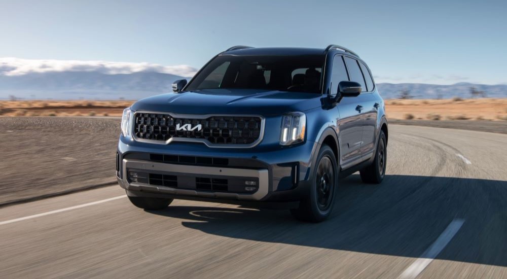 Black 2025 Kia Telluride for sale driving around a bend.