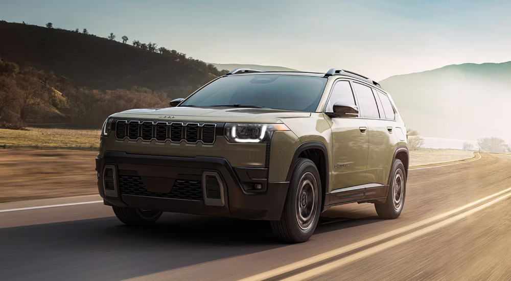 Green 2026 Jeep Cherokee driving down an empty road