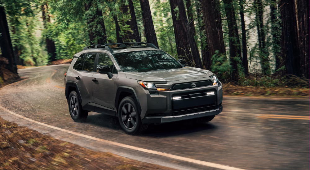 Green 2026 Toyota RAV4 driving down a wooded road
