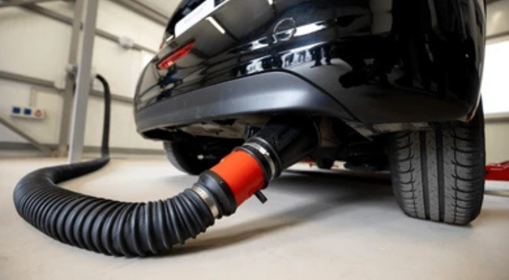 A black car gets an emissions test in an auto shop.