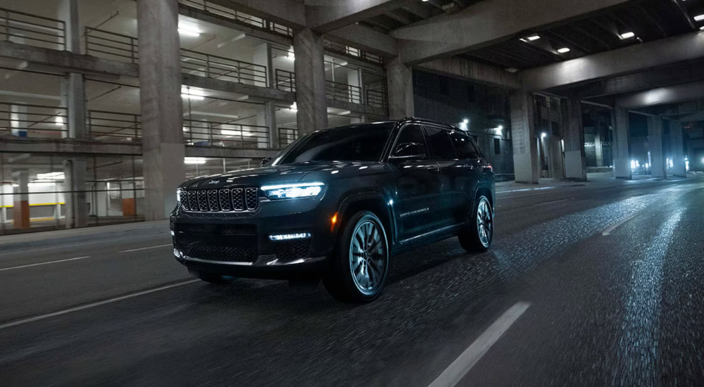 Black 2026 Jeep Grand Cherokee driving down an empty city street