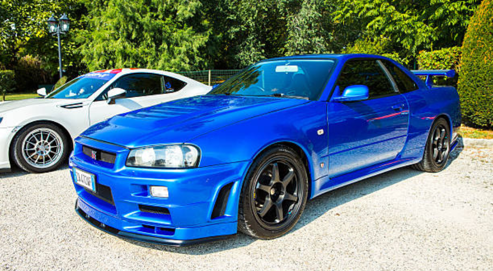 Blue 1999 Nissan Skyline GT-R parked on gravel