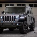 A black 2024 Jeep Wrangler 4xe plugged in to charge