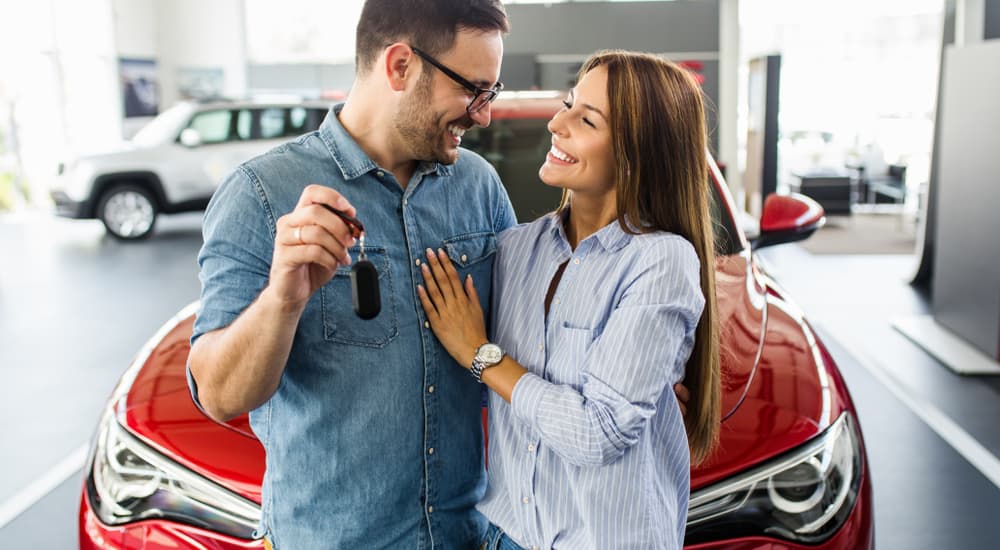 A couple holding car keys to the new car they purchased