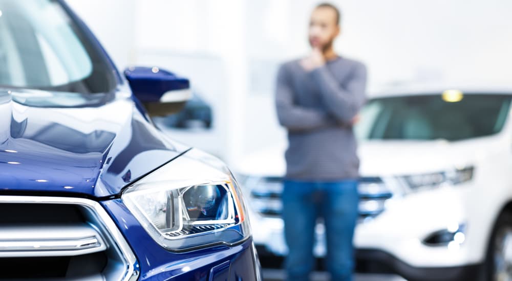 A man deciding between a white car and a blue car