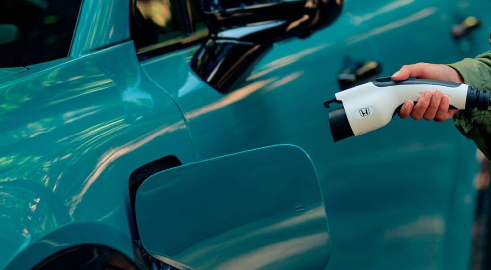 A light blue 2026 Honda Prologue is shown with a charger.