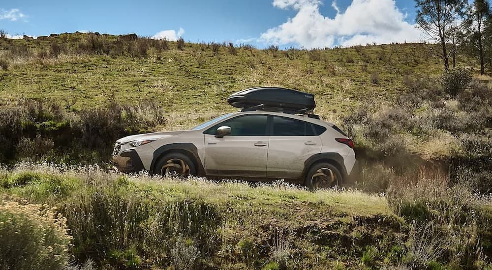 A tan 2026 Subaru Crosstrek Hybrid driving uphill.