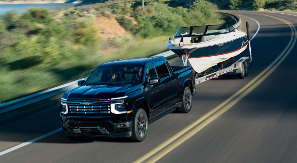 A black 2027 Chevy SIlverado 1500 High Country towing a boat.